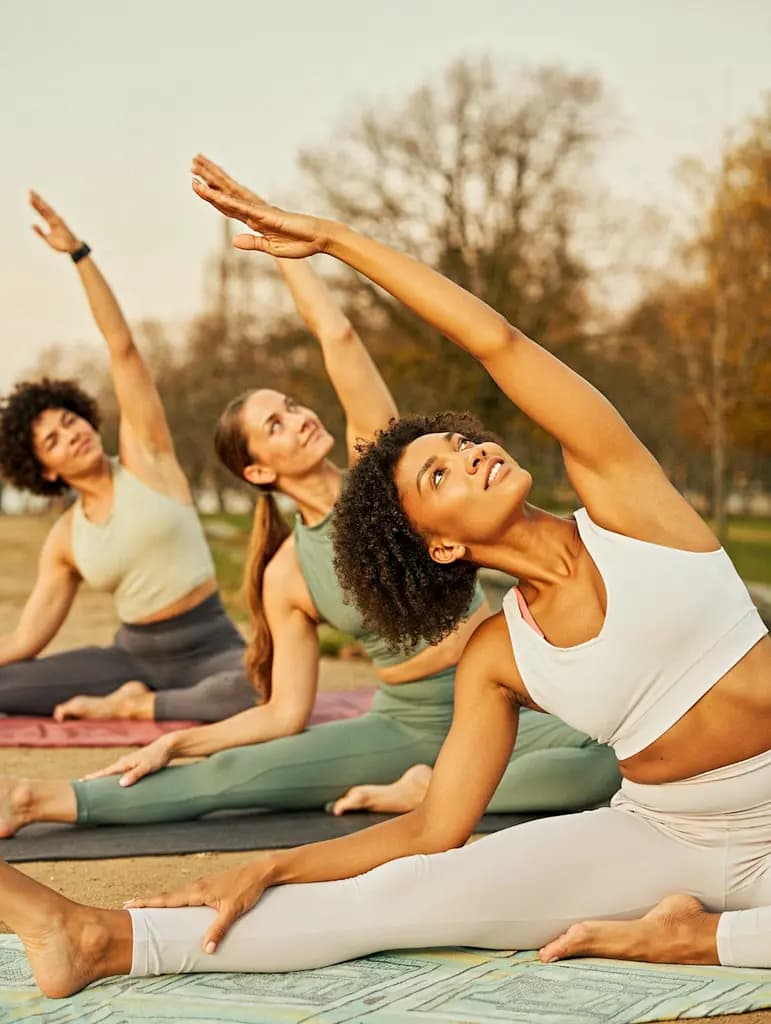 Group of women practicing yoga outdoors at sunrise in a park setting in the UAE